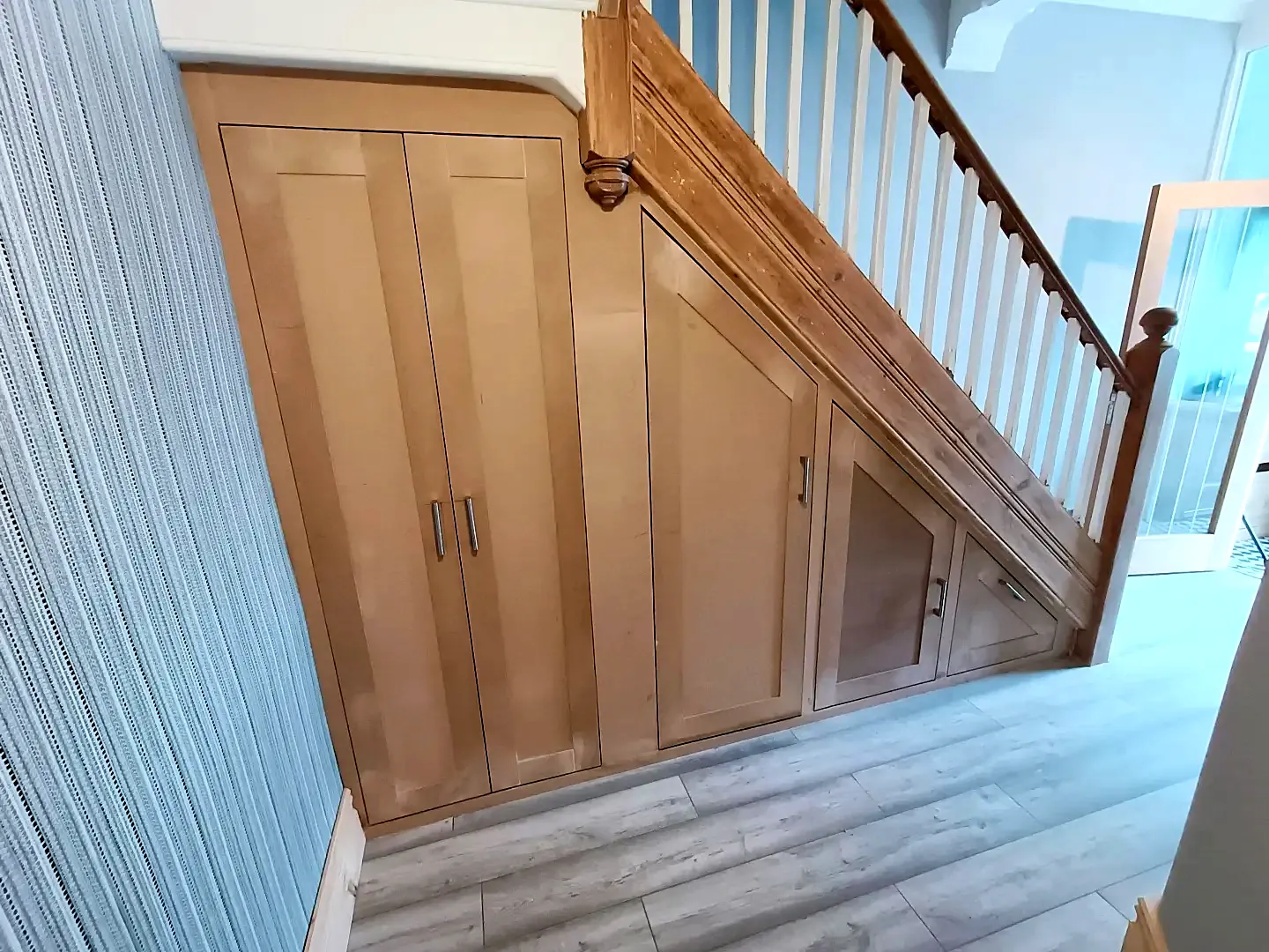 Under-stairs storage with shaker doors and cupboards following the line of the stairs
